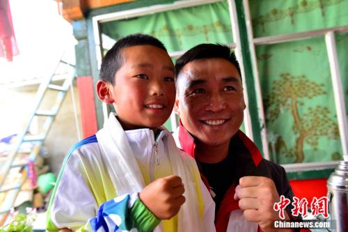  “星能冠军助学项目西藏行”活动由北京星能公益基金会主办，组织8位知名运动员进藏，计划对当地学习体育的孩子进行专业指导、扶助等。图为6月19日，2008年北京奥运会男子拳击81公斤级金牌得主张小平与西藏山南小运动员杰布比划拳击姿势，合影留念。 
江飞波 摄
